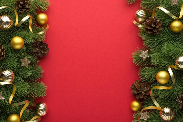 Top view photo of gold and silver christmas tree balls pine cones small stars and gold serpentine on pine branches on isolated red background with copyspace