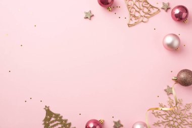 Noel ağacı süslemelerinin en üst görüntüsü pembe toplar altın çan çanı şekilli kar tanesi şekilli süsler parlayan yıldızlar yılan gibi ve izole edilmiş pastel pembe arka planda boş alan ile pullar.