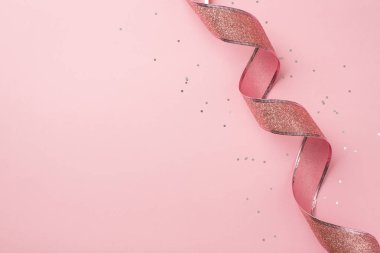 Sevgililer Günü dekorasyonunun en üstteki fotoğrafı pembe kıvrımlı kurdele ve pulları boş arkaplanlı izole pastel pembe arkaplanda parlıyor.
