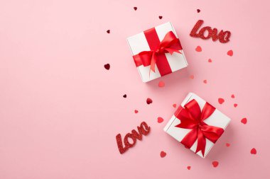 Sevgililer Günü süslemelerinin en üst görüntüsü kırmızı kurdeleli iki beyaz hediye kutusu sevgi ve kalp şeklinde konfetiler izole edilmiş pastel pembe arka planda kopyalanmış