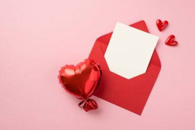 Sevgililer Günü dekorasyonunun en üst görüntüsü. Küçük kalpler. Kağıt çarşaf ve kalp şeklinde balon ile açık kırmızı zarf.