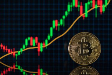 Altın sikkenin fotoğrafı, arka planda bitcoin sembolü var.