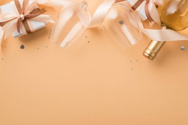 Sevgililer Günü dekoru şarap şişesi şarap kadehinin en üst görüntüsü parlayan kahverengi ve açık bej kurdeleli hediye kutuları izole edilmiş bej arka planda kalp şeklinde konfeti pulları.