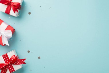 Sevgililer Günü dekorasyonunun en üst görüntüsü kalp konfeti şekilli parlak pullar ve izole edilmiş pastel mavi arka planda üç hediye kutusu.
