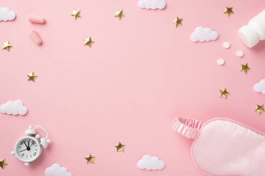 Top view photo of small white alarm clock pink silk sleeping mask earplugs bottle with pills golden stars and clouds on isolated pastel pink background with blank space in the middle