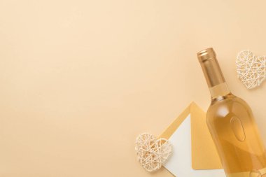 Top view photo of bottle of white wine decorative rattan hearts and envelope with paper sheet on isolated beige background with blank space
