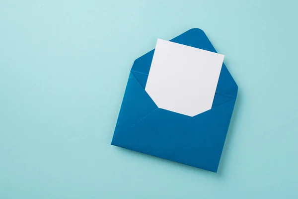 空の空間を持つ隔離されたパステルブルーの背景に紙シートとオープンブルーの封筒のトップビューの写真 — ストック写真