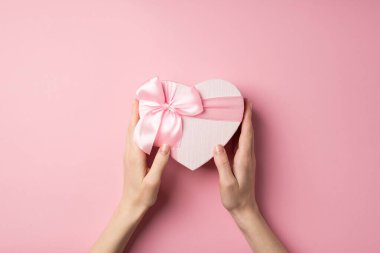 Sevgililer Günü süslemelerinin ilk resmi. Genç bir kadının ellerinde pembe kurdeleli kalp şeklinde bir hediye kutusu var.