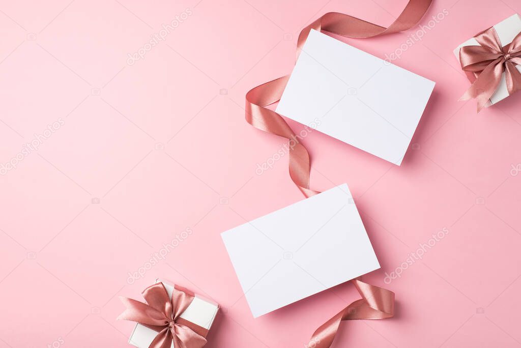 Top view photo of valentine's day decorations curly silk ribbon two small gift boxes with bows and two letters on isolated pastel pink background with copyspace