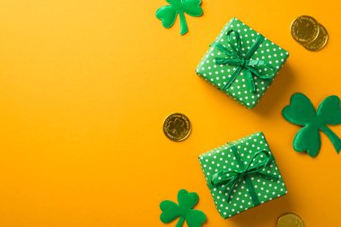 Aziz Patrick Günü 'nün en iyi fotoğrafı iki yeşil hediye kutusu içinde benekli yoncalar ve izole edilmiş sarı arka planda boş alan olan altın paralar.