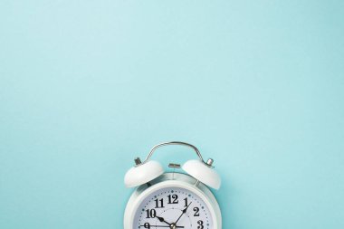 Klasik beyaz alarmlı saatin kesilen yarısının yukarıdaki görüntüsü. Açık renkli arkaplan üzerine izole edilmiş. Boş alan var.