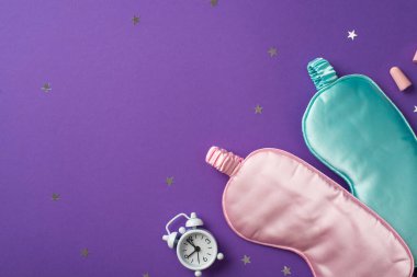Küçük beyaz saatin üst görüntüsü ve iki ipek göz bağı pembe ve açık mavi olanın dağınık konfetileri yıldız şeklinde ve menekşe izole edilmiş arka plan fotokopisinde iki kulak tıkacı.