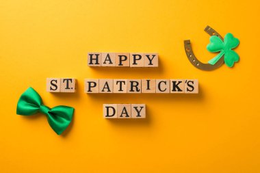 Ahşap küplerin en üstteki fotoğrafı Mutlu Aziz Patrick 'ler günü yeşil papyonlu yonca ve izole sarı arka planda at nalı