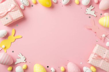 Paskalya süslerinin en üstteki fotoğrafı hediye kutuları konfeti kutuları paskalya tavşanları pembe ve beyaz paskalya yumurtaları izole edilmiş, pembe arka plan ve ortada boş alan.