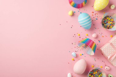 Paskalya süslemelerinin en üst görüntüsü pembe hediye kutusu çok renkli paskalya yumurtaları kağıt kalıpları izole edilmiş pastel pembe arka planda kalıplar ve şekerlemeler