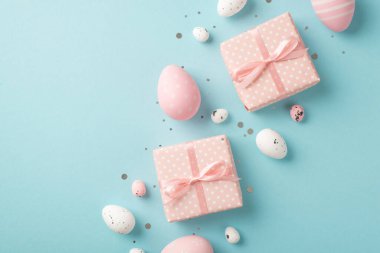Paskalya süslemelerinin en üstteki fotoğrafı iki pembe hediye kutusunda polka desenli pembe ve beyaz paskalya yumurtaları izole edilmiş pastel mavi arka planda ve kopyalanmış