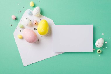 Paskalya süslemelerinin en üst görüntüsü konfeti beyaz zarf açık paskalya yumurtaları ve izole edilmiş turkuaz arka plan üzerinde kağıt kart boş alan