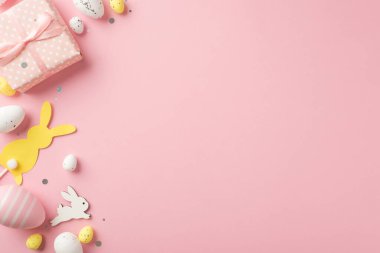 Paskalya dekorasyonunun en üst görüntüsü hediye kutusu pulları paskalya tavşanları izole edilmiş pastel pembe arka planda pembe ve beyaz paskalya yumurtaları boş alan.