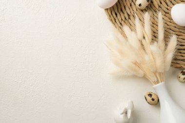 Paskalya süslemelerinin en üst görüntüsü vazo dolusu lagurus çiçeğiyle servis edilen seramik paskalya tavşanı ve izole edilmiş beyaz arka planda paskalya yumurtaları.