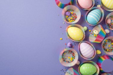 Paskalya dekorunun en üst görüntüsü parlak rengarenk küçük yıldızlar gökkuşağı yumurtaları farklı boyutlarda kek kutuları ve küçük olanlar izole edilmiş pastel menekşe arka planda boş alan