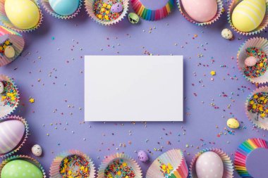 Beyaz kartın üst görüntüsü parlak renkli küçük yıldızlar gökkuşağı yumurtaları farklı boyutlarda kek kağıtları üzerinde pastel menekşe arka planda.