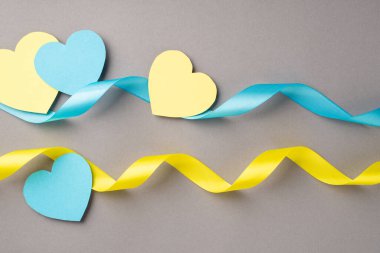 Ukrayna 'daki savaşı durdurun. Ulusal bayrak renklerinin üst görünümü mavi ve sarı kalpler ve izole edilmiş gri arkaplan üzerindeki dalgalı kurdeleler