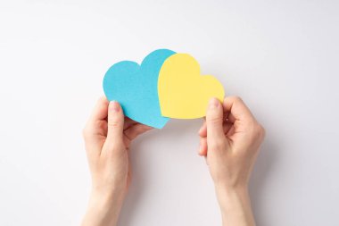 Ukrayna 'daki savaşı durdurun. Beyaz arka planda iki sarı ve mavi kalbi tutan genç kızın el fotoğrafı.