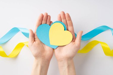 Ukrayna 'daki savaşı durdurun. Beyaz arka planda ulusal bayrak üzerinde avuçlarında sarı ve mavi kalplerle genç bir kızın ellerini gösteren ilk kişi.