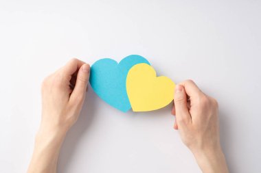 Ukrayna 'daki savaşı durdurun. Beyaz zemin üzerinde sarı ve mavi kalplerle boş alan tutan kadın ellerinin en üstteki görünümü