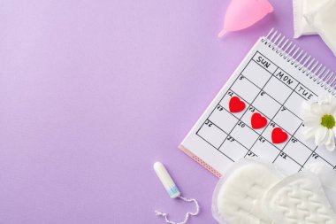 Takvimdeki kırmızı kalp izlerinin üst görüntüsü. Pembe adet bardağı periyodu. Tampon ve papatya tomurcukları.