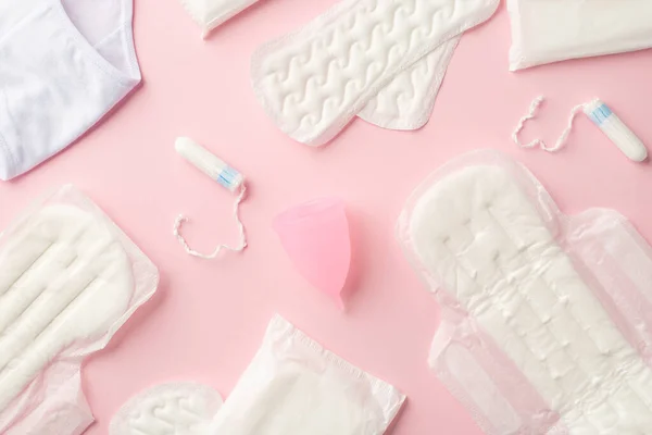 Top view photo of sanitary napkins lingerie menstrual cup and tampons on isolated pastel pink background