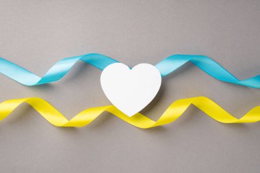 Ukrayna 'daki savaşı durdurun. Ulusal bayrak renkleri üzerinde beyaz kalbin en üstteki görüntüsü izole edilmiş gri arkaplan üzerinde mavi ve sarı dalgalı kurdeleler ve boş alan