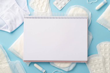 Hijyenik peçeteler, iç çamaşırları ve soluk mavi arkaplan üzerine haplar üzerinde açık planlayıcının en iyi fotoğrafı.