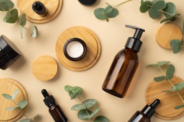 Plastik konsept yok. Cam şişelerin, okaliptüslerin, okaliptüs yapraklarının ve ahşabın izole bej arka planda durduğu en üst görüntü.