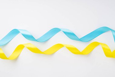 Ukrayna 'daki savaşı durdurun. İzole edilmiş beyaz zemin üzerinde ulusal bayrak renklerinin üst görünümü sarı ve mavi dalgalı kurdeleler