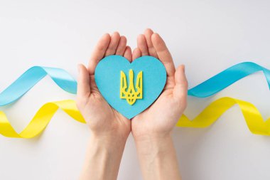 Ukrayna 'daki savaşı durdurun. Beyaz arka planda ulusal bayrak üzerinde avuçlarında altın mızrakla mavi kalbi tutan genç kızın ilk resmi.