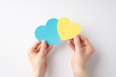 Ukrayna 'daki savaşı durdurun. Beyaz arka planda iki sarı ve mavi kalp tutan bir kızın el fotoğrafı.