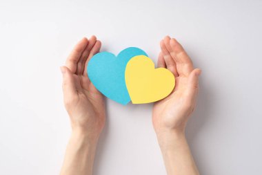 Ukrayna 'daki savaşı durdurun. Kadın elinin beyaz arka planda iki sarı ve mavi kalp verdiği ilk kişi.