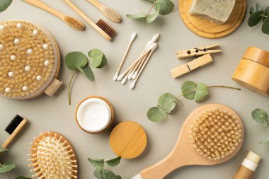 Spa aksesuarları antiselülit saç fırçası krem boru sabunu ahşap ayakta duruyor diş fırçası tomurcukları çamaşır fırçası ve okaliptüs izole edilmiş pastel gri arka planda.