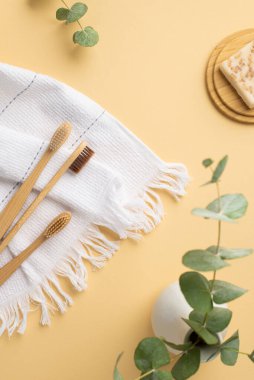 Okaliptüs beyaz pamuk diş fırçası ve bambu üzerinde sabun bulunan vazonun dikey fotoğrafı izole edilmiş pastel bej arka planda duruyor.