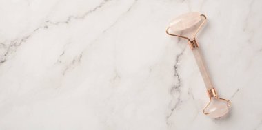 Cilt bakımı. Beyaz mermer zemin üzerinde gül kuvars silindiri boş alan ile üst görünüm fotoğrafı