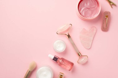 Güzellik prosedürü konsepti. Rose Quartz 'ın en iyi görüntü fotoğrafı gua sha makyaj malzemeleri pembe göz bantları cam saç tokaları ve izole edilmiş pastel pembe arka planda krema kavanozları.