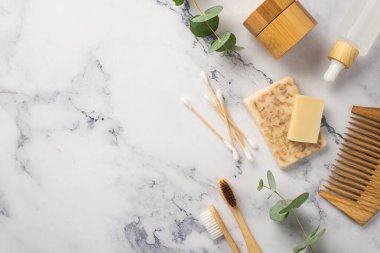 Eko kozmetik konsepti. Sabun şişelerinin üst görüntüsü pamuk tomurcukları bambu saç fırçası diş fırçaları ve okaliptüs filizi beyaz mermer arka planda ve kopyasal alan