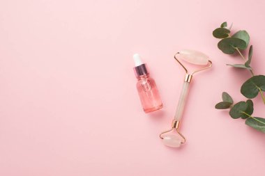 Cilt bakım prosedürü konsepti. Okaliptüs gül kuvars silindiri ve şeffaf pembe cam şişenin izole edilmiş pastel pembe arka plan ve kopyalanmış