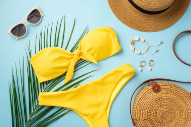 Yaz tatili kavramı. Şapka kabuğundan bileziğin üst görüntüsü küpeler şık güneş gözlükleri sarı bikini yuvarlak rattan çanta ve izole edilmiş pastel arka planda palmiye yaprakları