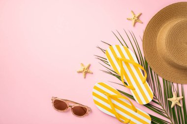 Summer rest concept. Top view photo of sunhat yellow striped flip-flops sunglasses starfishes and palm leaves on isolated pastel pink background with copyspace