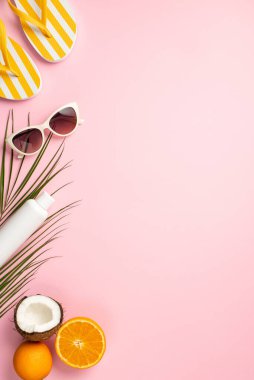 Yaz tatili konsepti. Güneş gözlüğü şişesinin dikey resmi Hindistan cevizi portakalları ve kopyalanmış pastel pembe arka planda palmiye yaprakları.