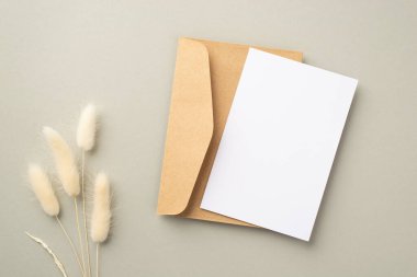 İş konsepti. Kağıt kaplama kağıt zarf ve pastel gri arkaplan üzerinde beyaz lagurus çiçekleri fotoğraf boş alan