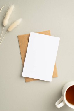 Kağıt kartların dikey fotoğrafı. Bir fincan çay ve pastel gri arka planda beyaz lagurular. Boş alan.