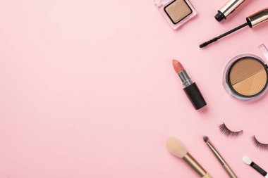 Güzellik konsepti uydur. Palet ruj, sahte kirpikler makyaj fırçaları, rimel ve göz farı boş arkaplanlı pastel pembe renkte.